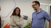 Two colleagues smiling and chatting in an office, standing near a printer with a colorful wall behind them